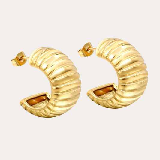 Gold hoop earrings on a light beige background